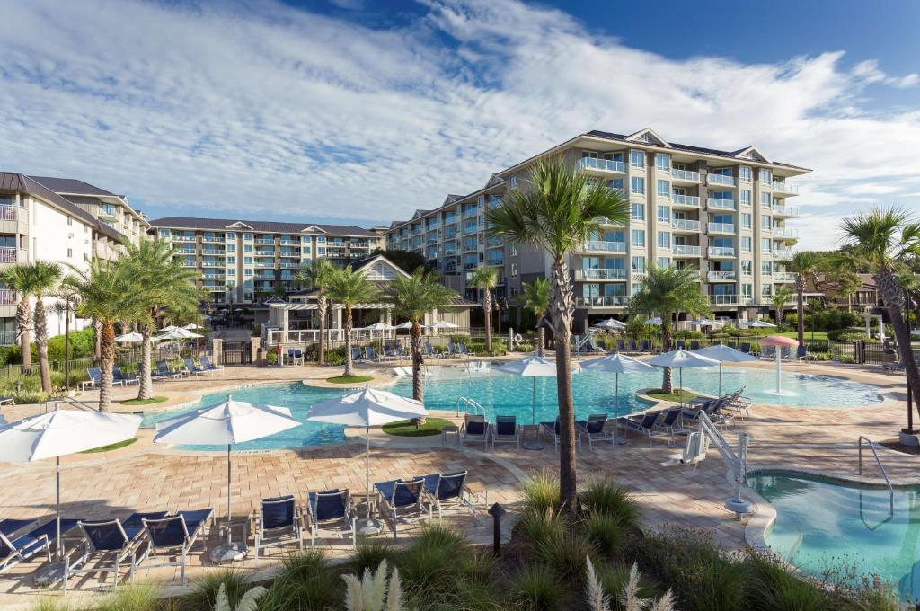 希尔顿黑德岛Hilton Grand Vacations Club Ocean Oak Resort Hilton Head的一张带椅子和遮阳伞的度假村游泳池的图片