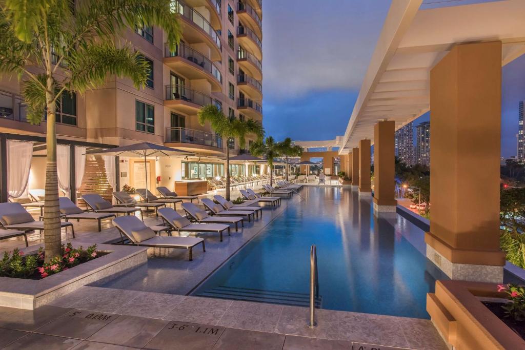 檀香山Hilton Grand Vacation Club The Grand Islander Waikiki Honolulu的一张酒店游泳池的图片,游泳池里摆放着躺椅和棕榈树