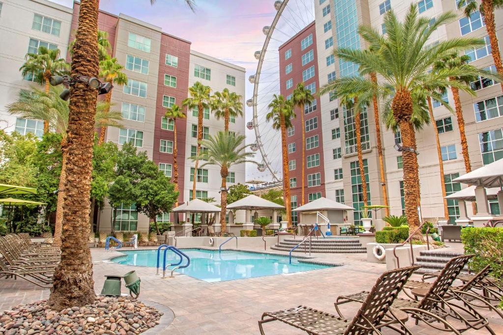 拉斯维加斯Hilton Grand Vacations Club Flamingo Las Vegas的一个带椅子和棕榈树的游泳池,以及建筑