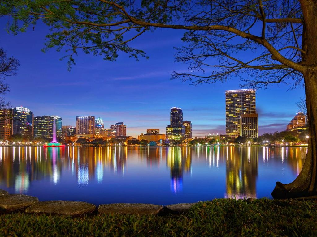 奥兰多Embassy Suites by Hilton Orlando Downtown的城市天际线在夜间反射到水面