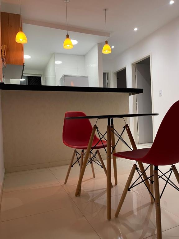 彼得罗利纳Apto Garagem Wifi Condomínio Piscina Ar-condicionado 2 Quartos的餐桌和2把红色椅子