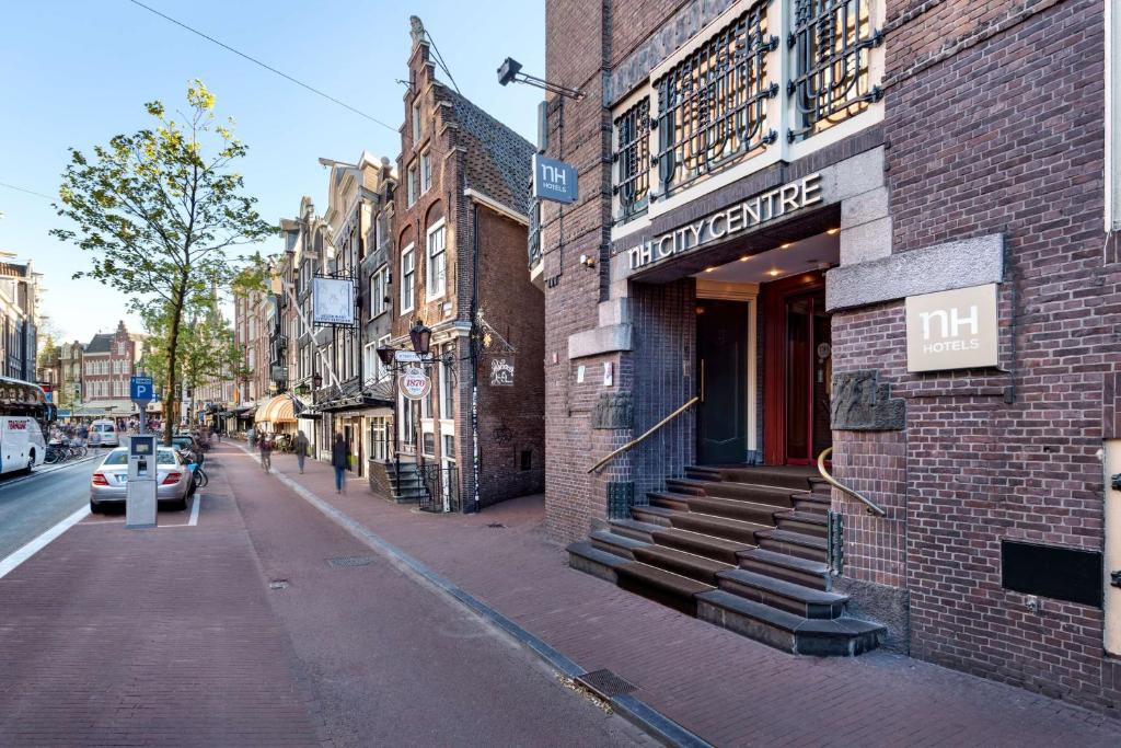 阿姆斯特丹阿姆斯特丹市中心NH酒店的城市街道上的砖砌建筑,有商店