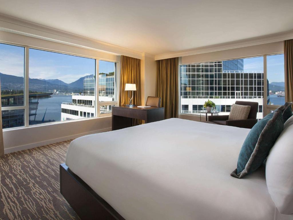 温哥华Fairmont Waterfront的一间酒店客房,设有一张大床和一个大窗户