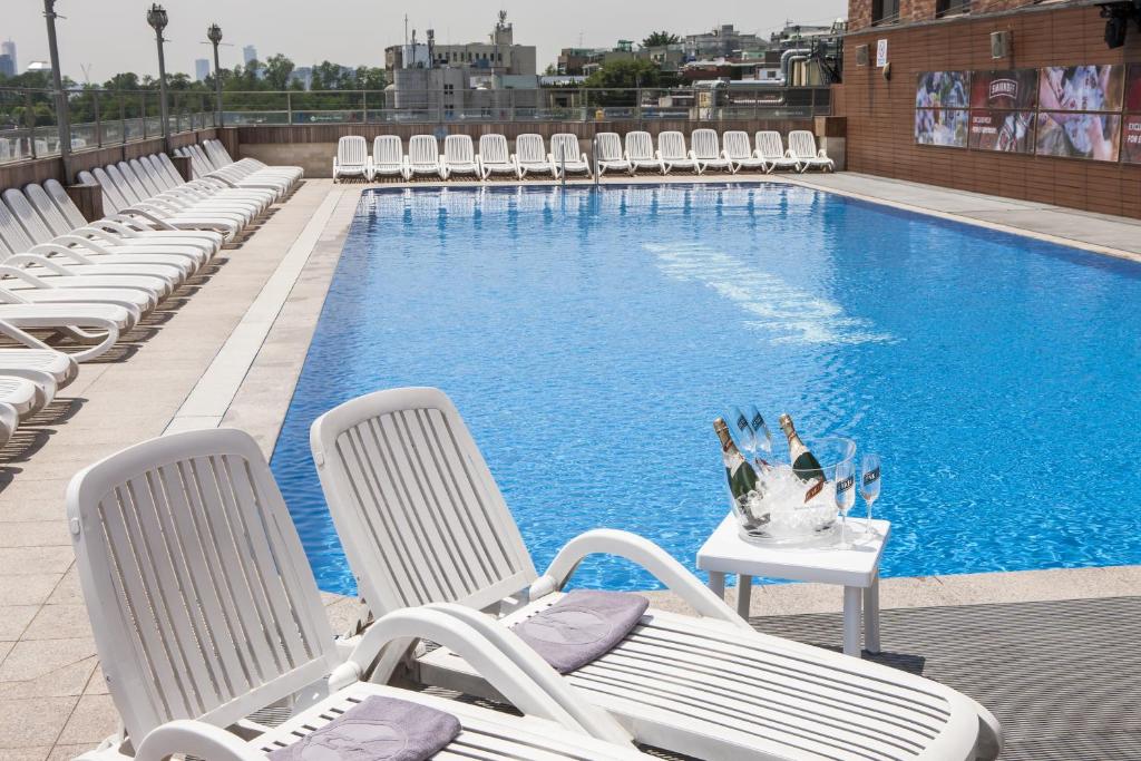 首尔哈密尔顿酒店的一个带椅子和桌子的游泳池,上面有花瓶