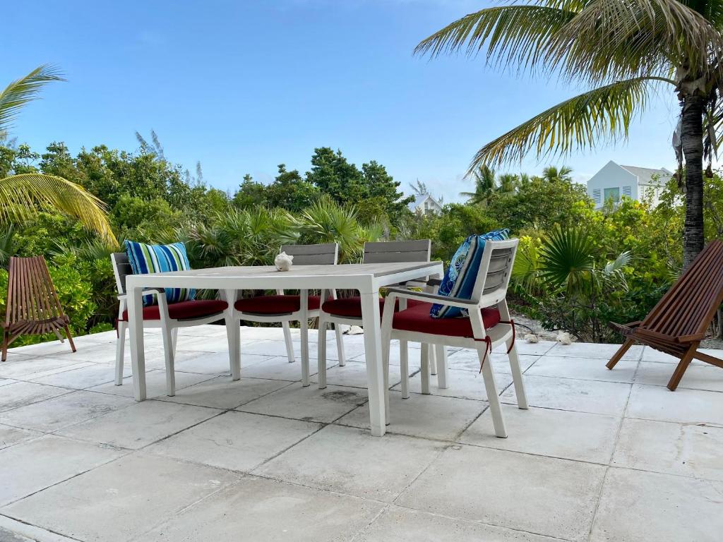 普罗维登西亚莱斯岛SeaSide Townhome, Spacious 2br 3bath Leeward Grace Bay, Providenciales, walk to beach的棕榈树庭院里的白色桌椅