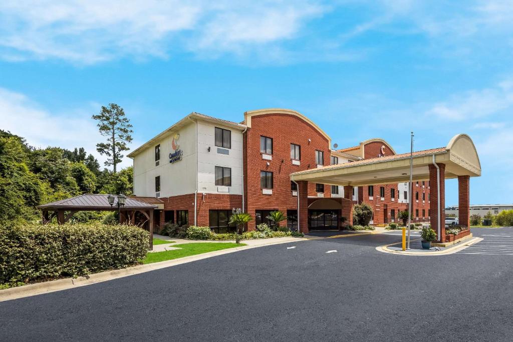 米德韦Comfort Inn & Suites Midway - Tallahassee West的街道旁的一座大型砖砌建筑,设有加油站