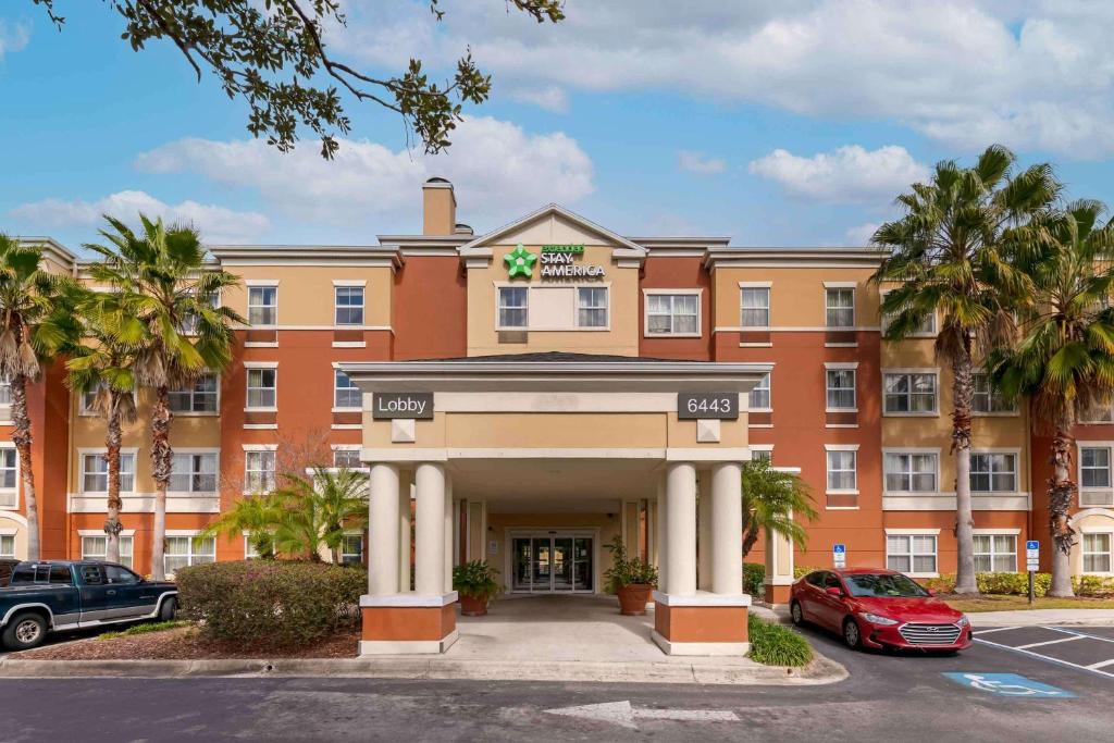 奥兰多美国长住酒店 - 奥兰多会议中心6443维斯特伍德的一座种植了棕榈树的大型橙色建筑