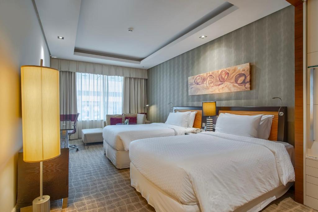 迪拜Majestic Premier Hotel Burdubai的酒店客房设有两张床和一张桌子。