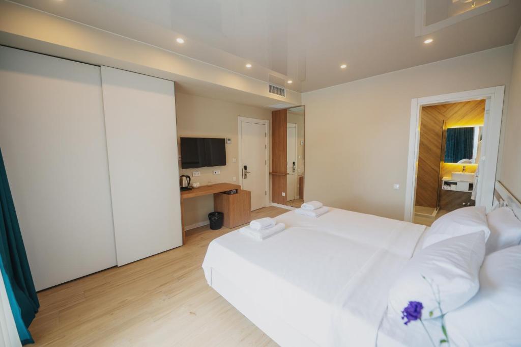 乌雷基Ritsa Resort的卧室配有一张白色大床和电视。