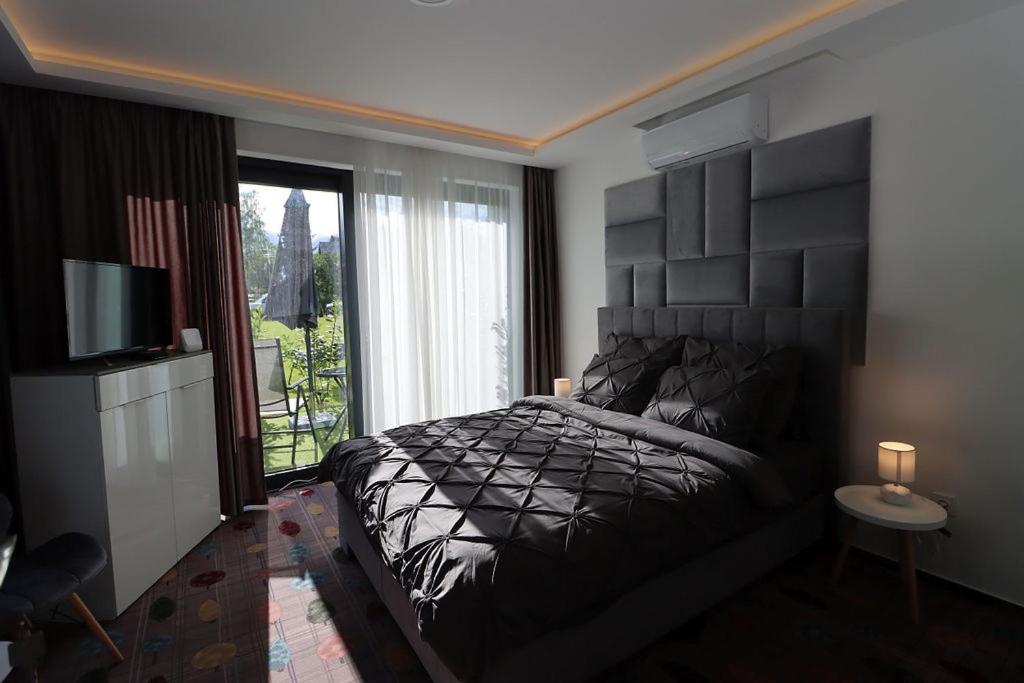 米什科尔茨Prestige Miskolctapolca的一间卧室设有一张黑色的床和一个窗户。