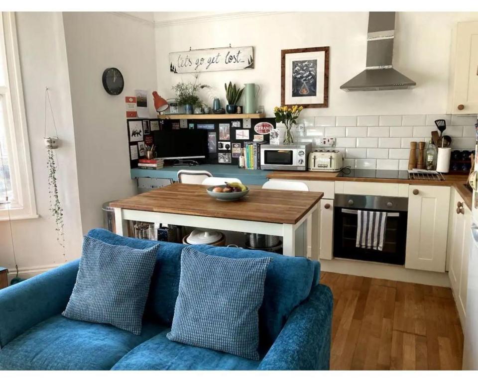 布里斯托Bright, book-filled flat in artsy Stokes Croft的一间带蓝色沙发的客厅和一间厨房