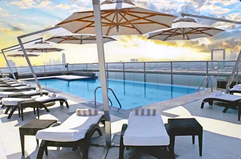 迪拜瑞吉斯公园克里斯金酒店的大楼内带桌子和遮阳伞的游泳池