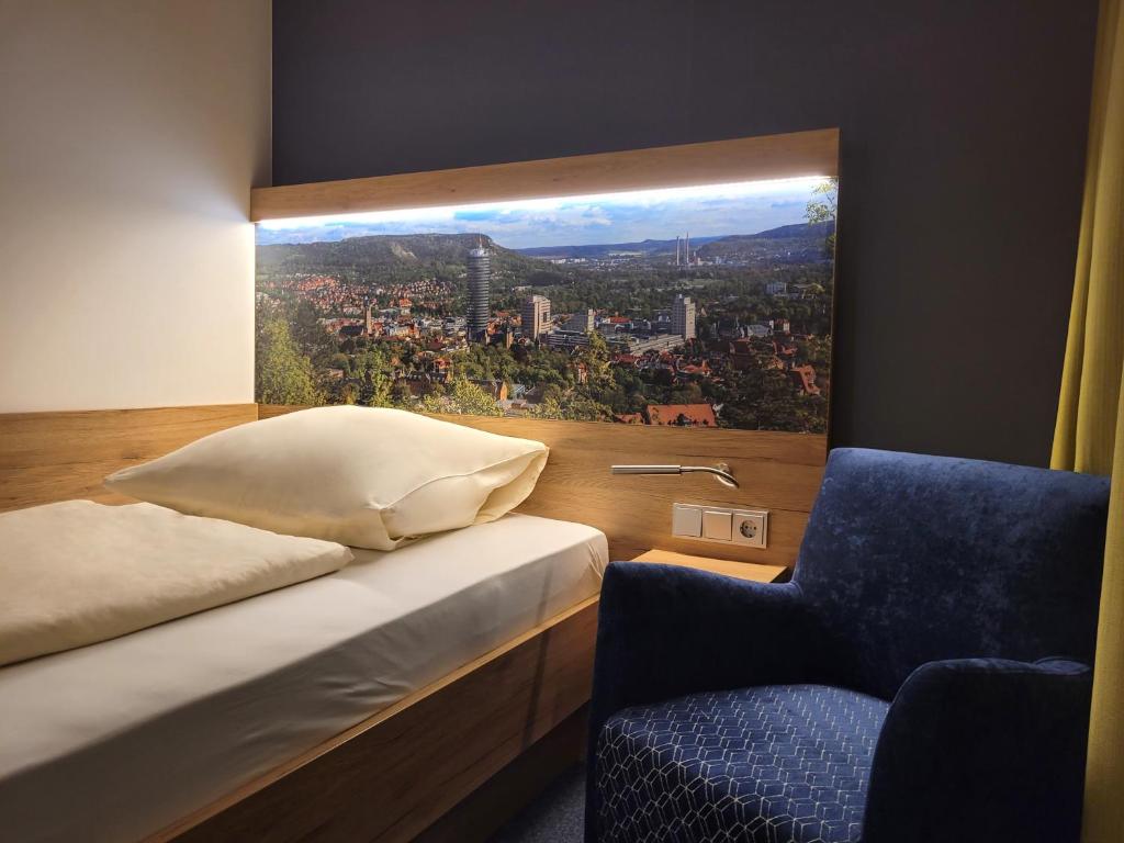 耶拿耶拿阿卡德米亚酒店的卧室设有窗户、一张床和一把椅子