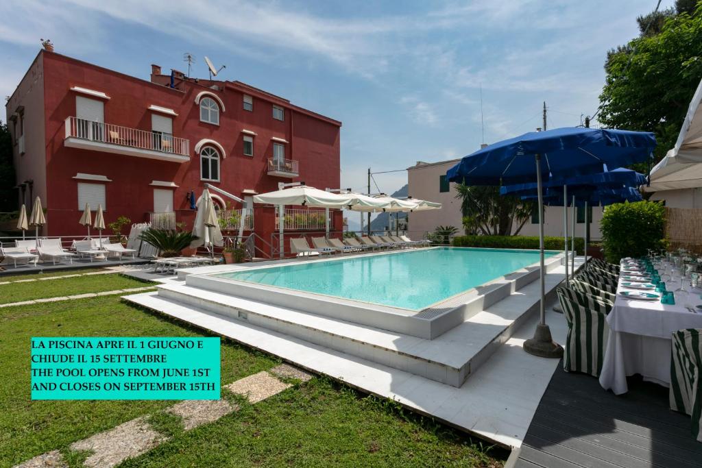 卡普里帕拉蒂姆马里酒店的一座红色建筑前的游泳池