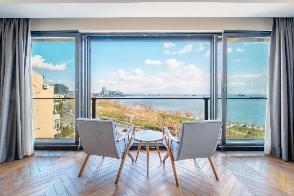 伊斯坦布尔Homie Suites - Newly Built Seaside Apartments on Bakırköy Shore的一间带桌椅和大窗户的用餐室