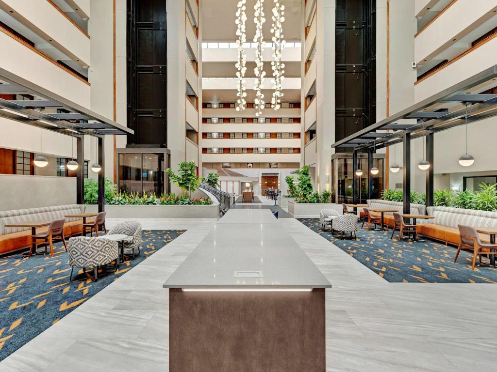 俄克拉何马城Embassy Suites by Hilton Oklahoma City Will Rogers Airport的一间设有桌椅的酒店空闲的大堂