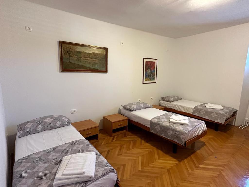 MaterijaHostel on the road trip的客房设有三张床,铺有木地板。