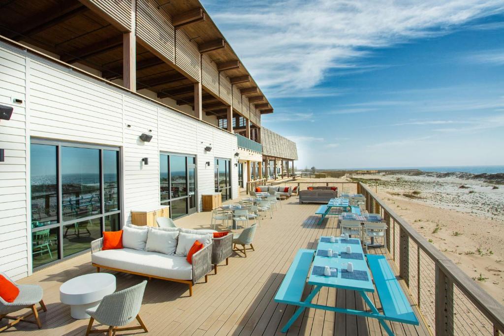 格尔夫海岸The Lodge at Gulf State Park, A Hilton Hotel的海滩上带桌子和沙发的甲板