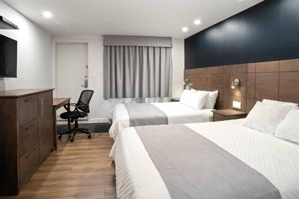 拉图克Hôtel Marineau Centre的酒店客房配有两张床和一张书桌