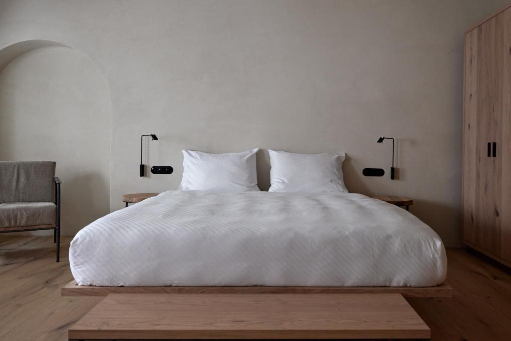 Brixenfink Restaurant & Suites的一间卧室配有一张带两盏灯的大型白色床。
