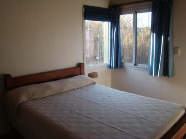 巴克罗斯Cabañas Mayma的一间卧室配有一张带蓝色窗帘的床和两个窗户。