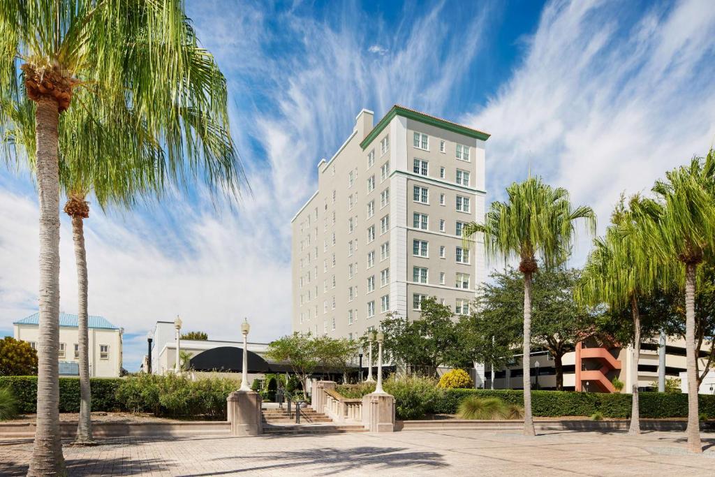 莱克兰The Terrace Hotel Lakeland, Tapestry Collection by Hilton的一座高大的白色建筑,前面有棕榈树
