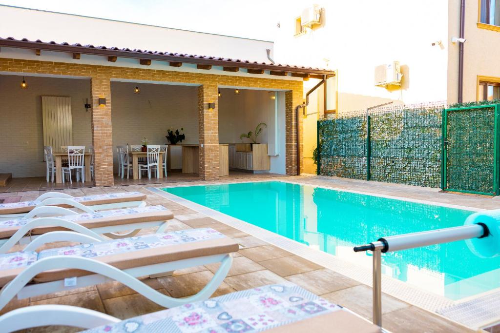 阿尔巴尤利亚Casa cu Nuc GRILL&POOL的一个带躺椅的游泳池以及一座房子