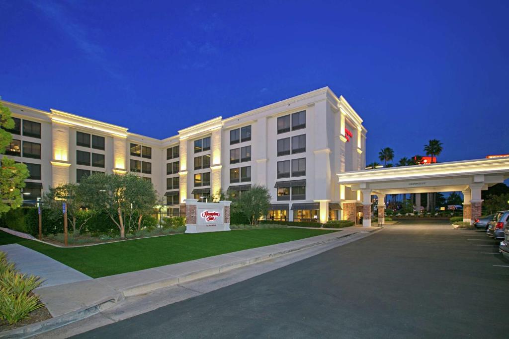 圣地亚哥Hampton Inn by Hilton San Diego - Kearny Mesa的一座白色的大建筑,前面设有停车场