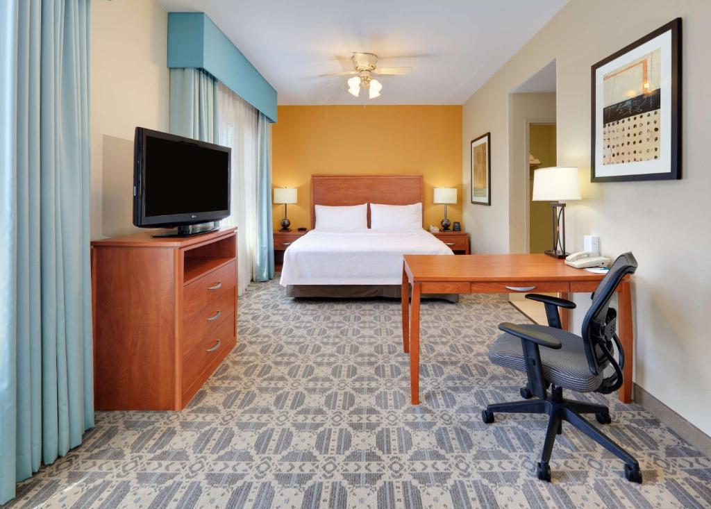欧文欧文-DFW机场希尔顿惠庭套房酒店的酒店客房配有一张床、一张书桌和一台电视。