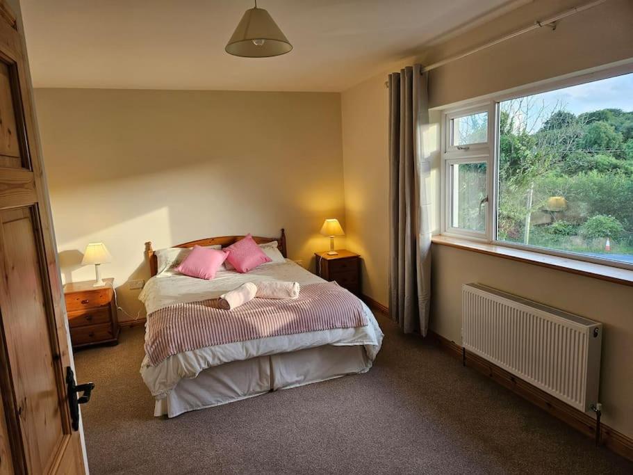 Hillview House的一间卧室配有带粉红色枕头的床和窗户。