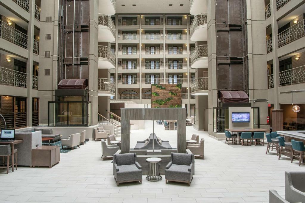 绍姆堡Embassy Suites by Hilton Chicago Schaumburg Woodfield的一座配有桌椅的建筑的空旷大堂