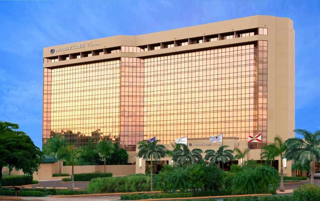 迈阿密希尔顿逸林酒店迈阿密机场和会议中心的一座黄色的大建筑,前面有棕榈树