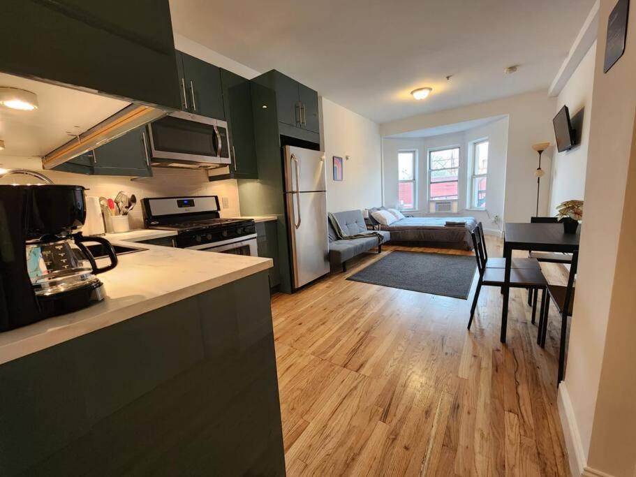 联城Deluxe Studio minutes from NYC!的一个带绿色橱柜的厨房和一间客厅