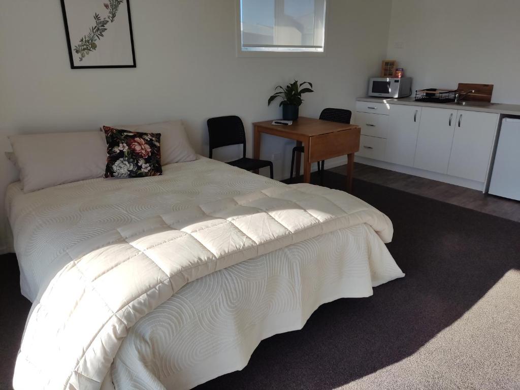 WairoaThe Ferry Hotel的卧室配有白色的床和桌椅