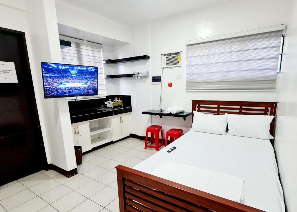 达斯马里尼亚斯Dasma Lofts Hotel near Dela Salle Dasma的一间卧室配有一张床和一台平面电视
