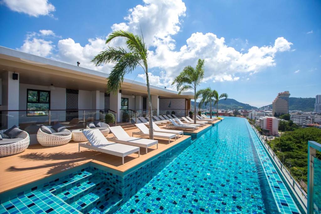 芭东海滩The Marina Phuket Hotel的酒店游泳池设有躺椅和棕榈树