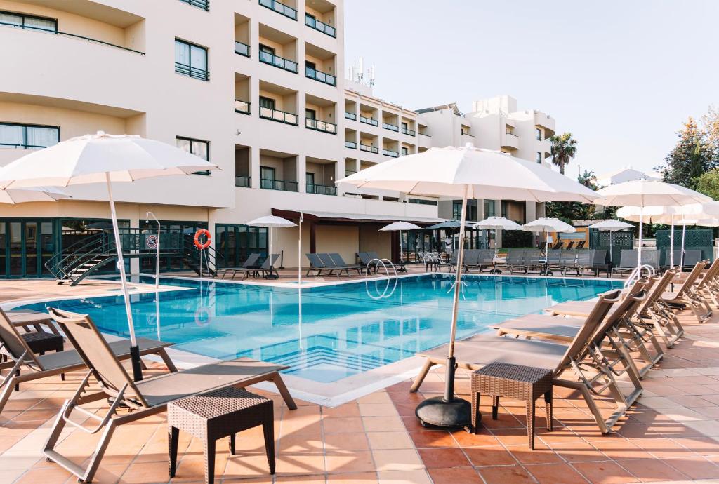 阿尔布费拉皇家贝拉维斯塔温泉酒店的大楼前的游泳池配有椅子和遮阳伞