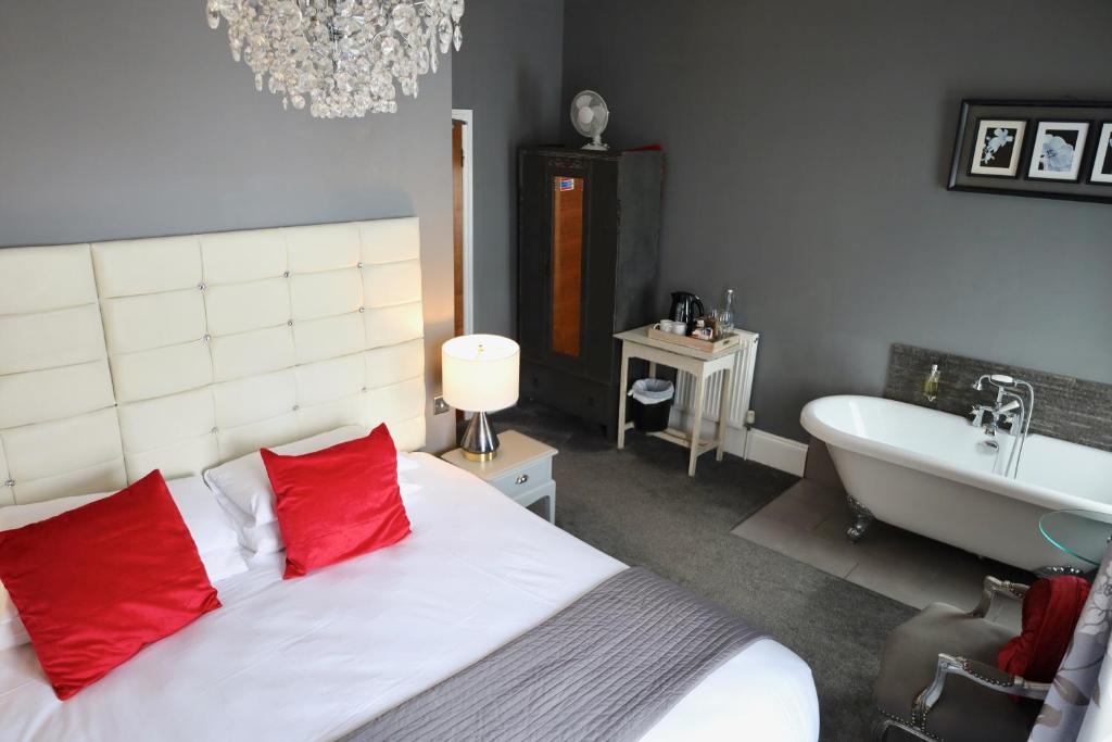 布莱顿霍夫布莱顿精品酒店的一间卧室配有一张带红色枕头的床和浴缸