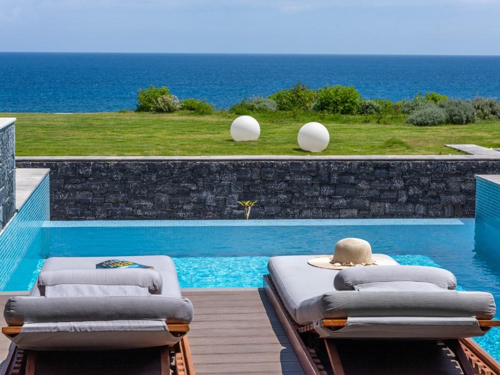 赫索尼索斯Nana Princess Suites Villas & Spa的一个带两张躺椅的游泳池,位于海边
