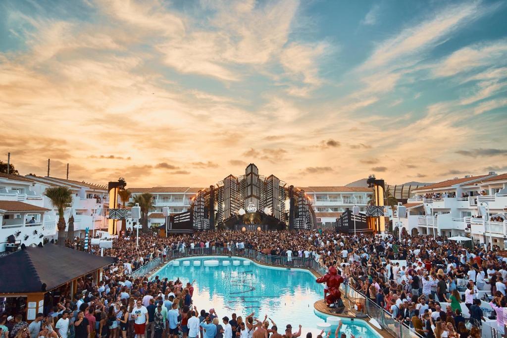 普拉亚登博萨Ushuaia Ibiza Beach Hotel - Adults Only-Entrance to Ushuaia Club included的一群人站在一个游泳池周围,在狂欢节