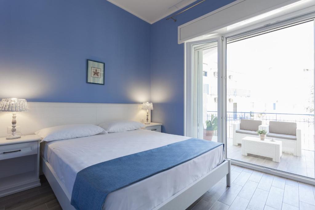 加利波利Costa Azzurra Gallipoli的蓝色的卧室设有床和大窗户