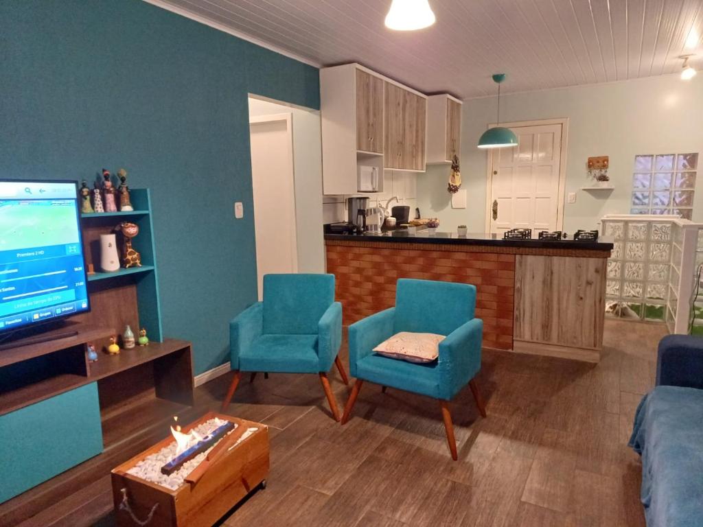 卡内拉Casa na Serra Gaucha Canela的一间带蓝色椅子的客厅和一间厨房