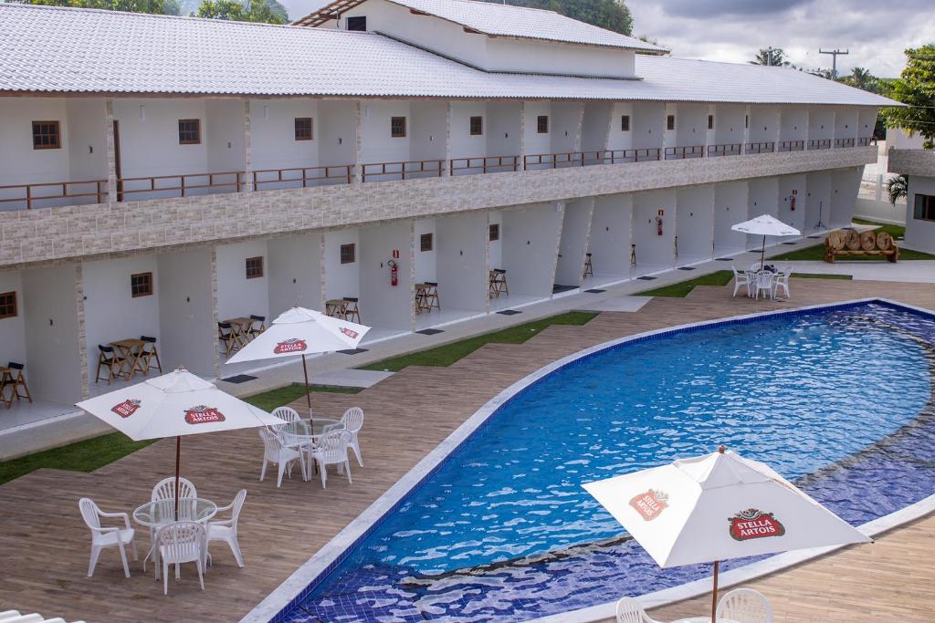 拉巴拉德纳圣安东尼奥Paraiso Barra Hotel的享有酒店高空的景色,设有游泳池、桌子和遮阳伞