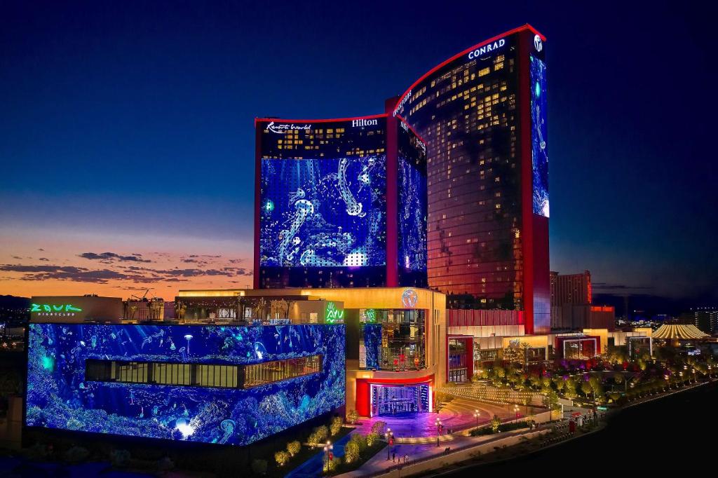 拉斯维加斯Crockfords Las Vegas, LXR Hotels &amp; Resorts at Resorts World的一座大建筑,晚上有蓝色的灯光