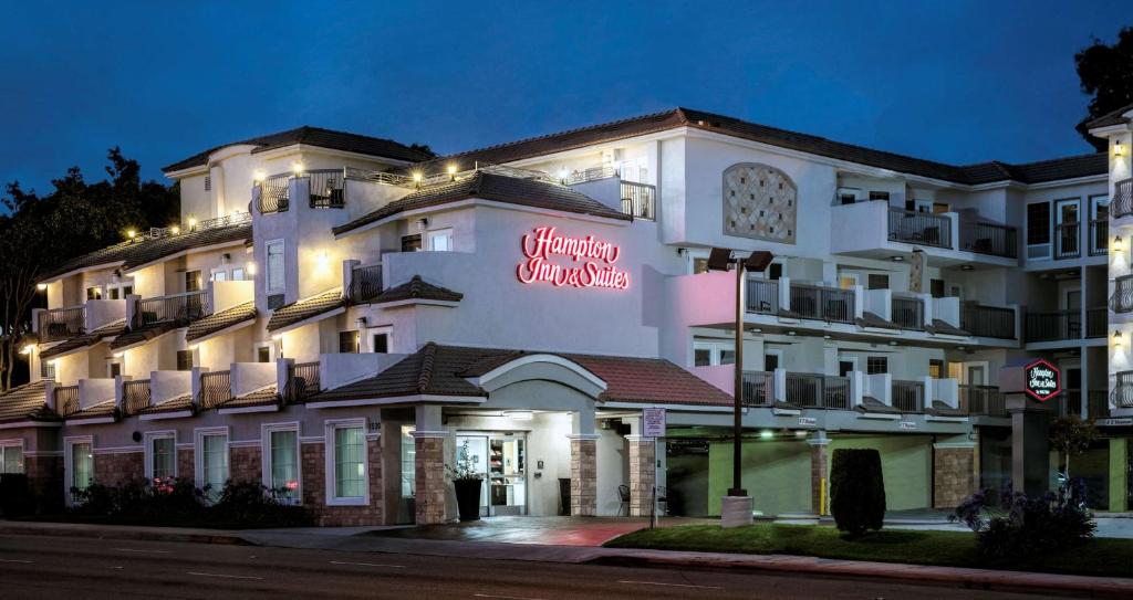 贺茂沙海滩赫莫萨比奇汉普顿套房酒店的一座白色的大建筑,上面有 ⁇ 虹灯标志
