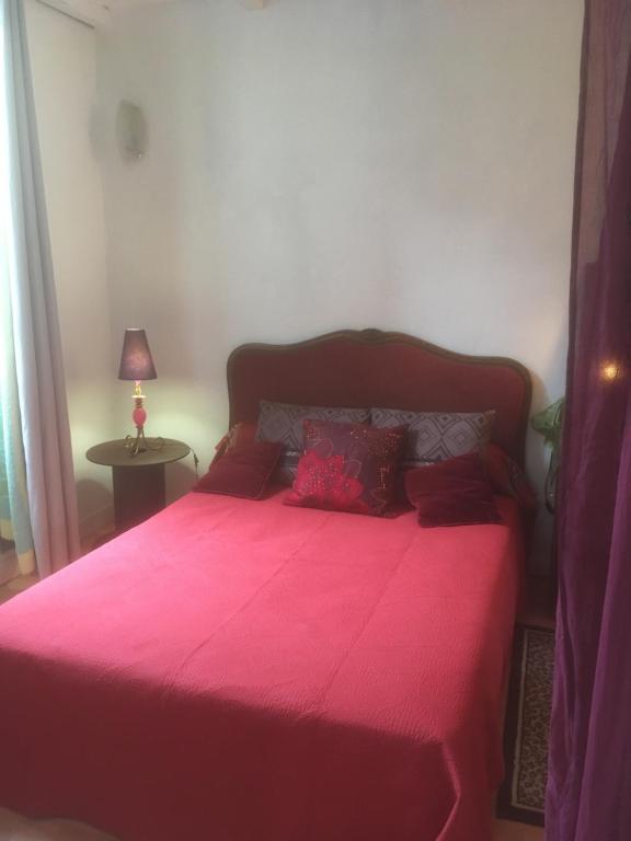 Corneilla-de-ConflentLes Arches du Cloître的一间卧室配有一张粉红色的床和红色毯子