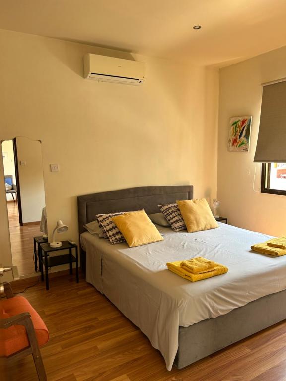 拉纳卡Extremely comfy apt with spacious private terrace 10min walk to the beach & in Town的一间卧室配有一张带黄色枕头的大床