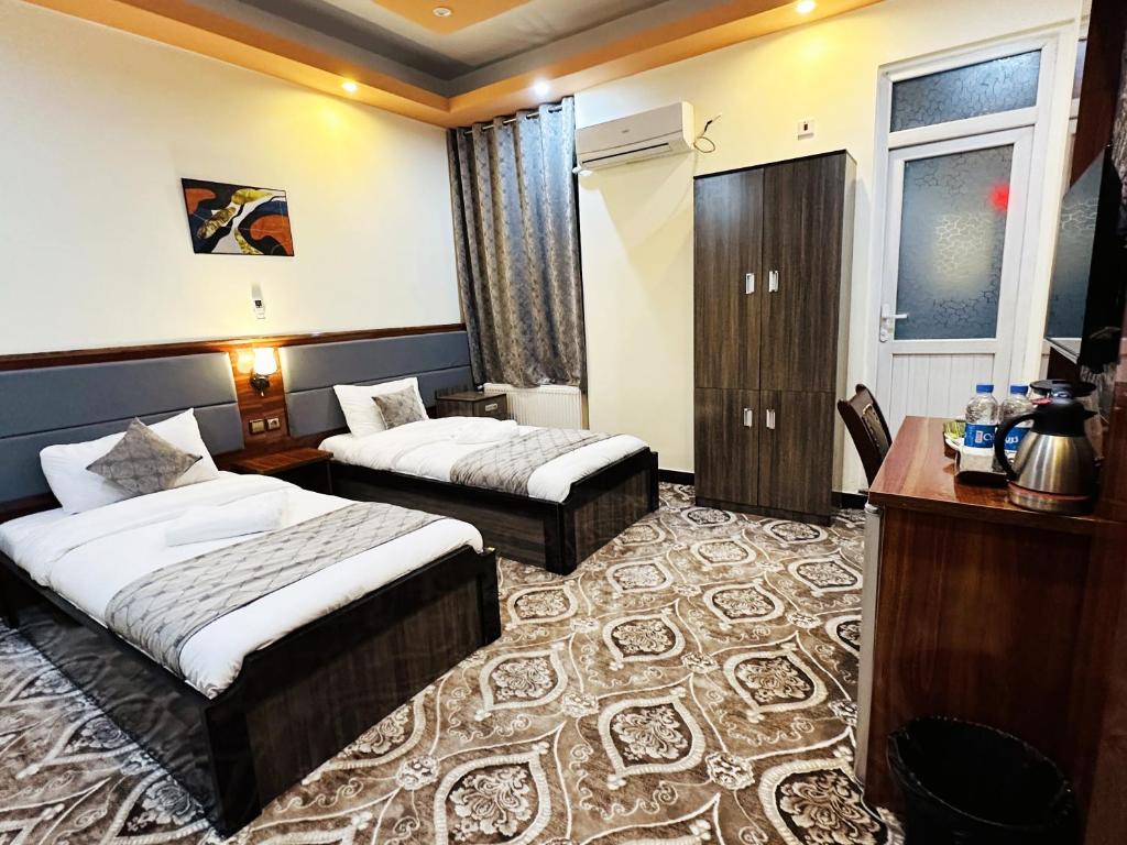 喀布尔Khyber Hotel的酒店客房配有两张床和一张书桌