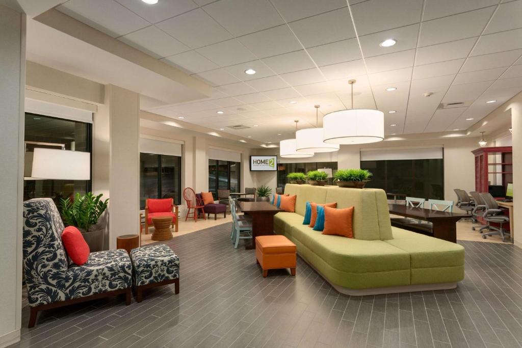 戈尔兹伯勒Home2 Suites By Hilton Goldsboro的一间设有绿色沙发和椅子的等候室