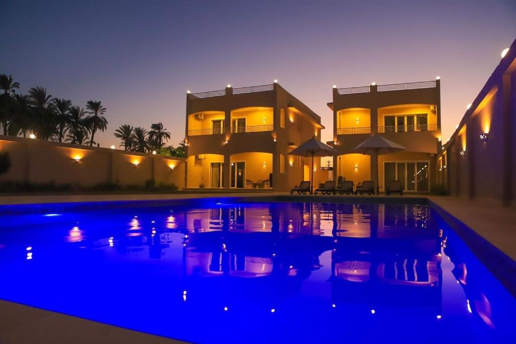 卢克索Royal Nile Villas - Nile View Apartment 1的一座在晚上设有游泳池的大房子